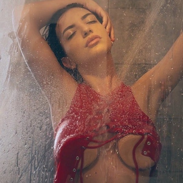 Zahra smit under the shower while touching the glass wall with her breasts and combing her hair with her hands