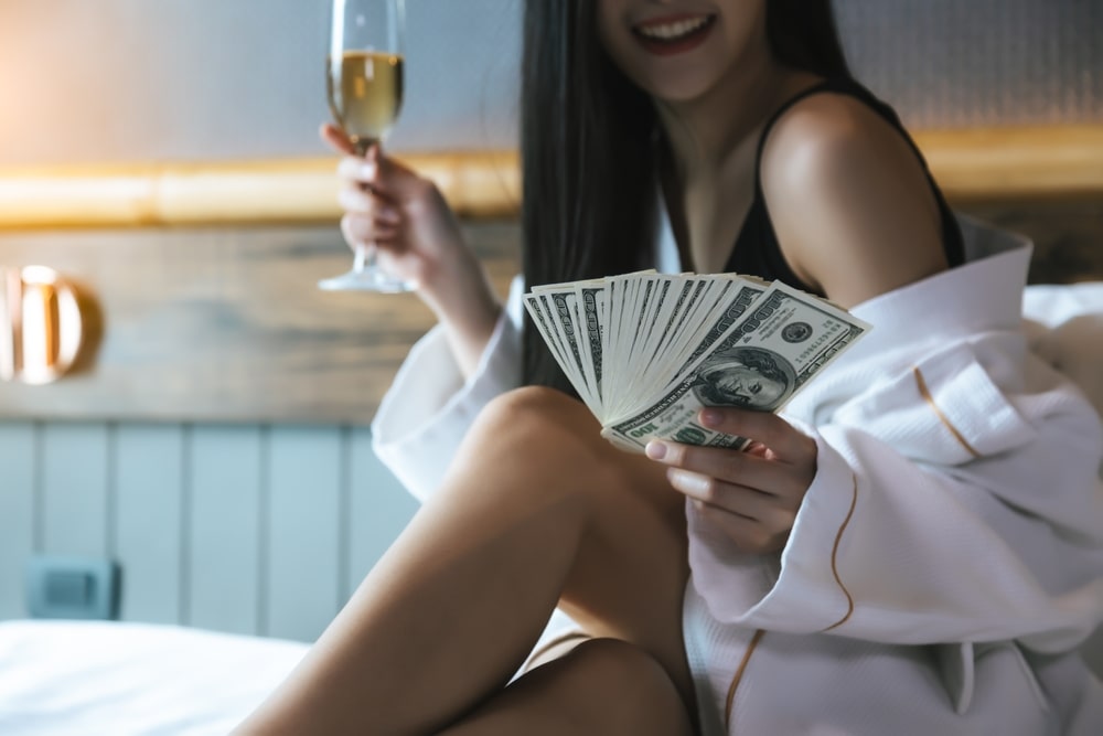 young sexy woman holding glass of champagne and money in her hand